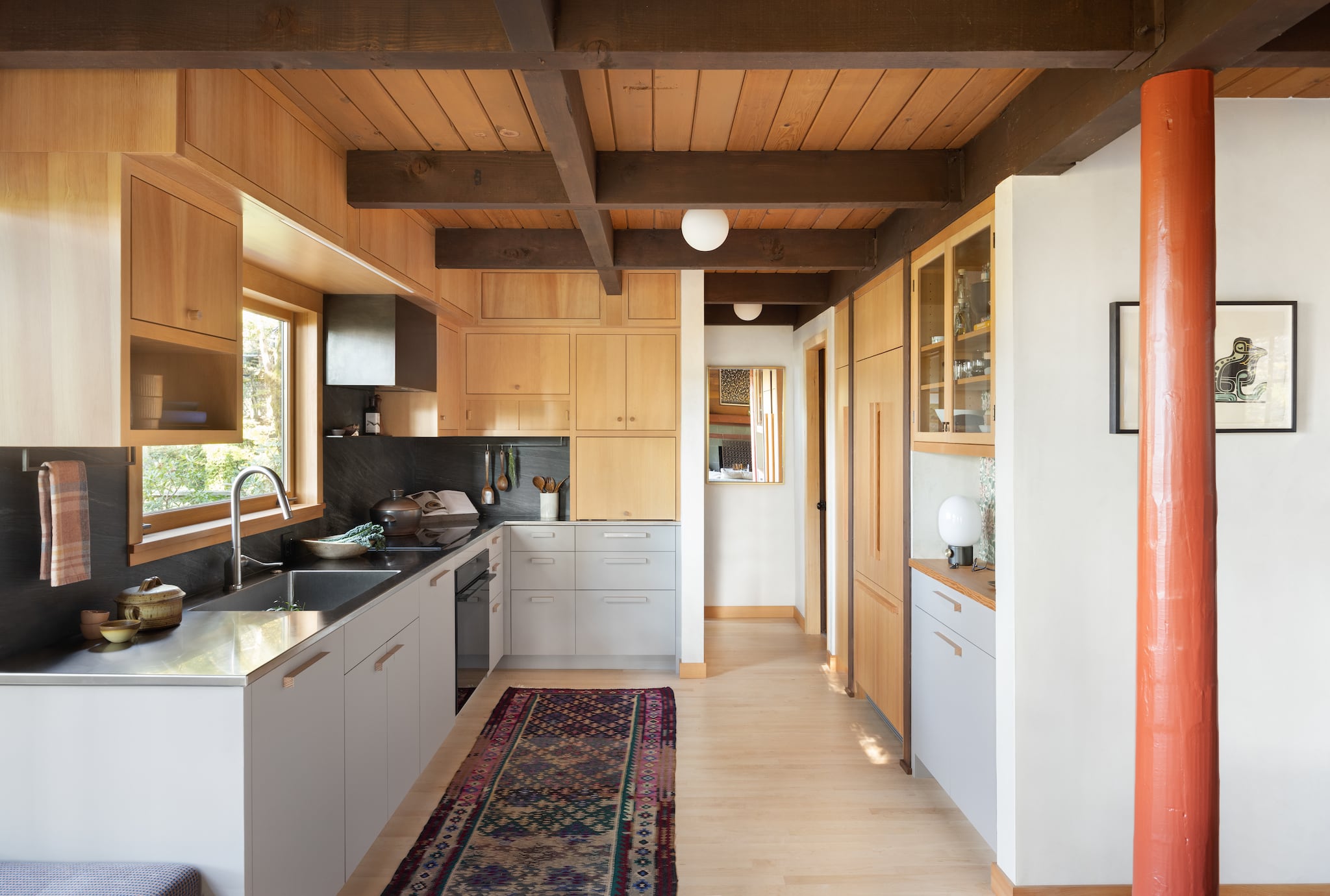 Detail of stainless steel countertop with induction stovetop, utensil rack, cherry cabinets